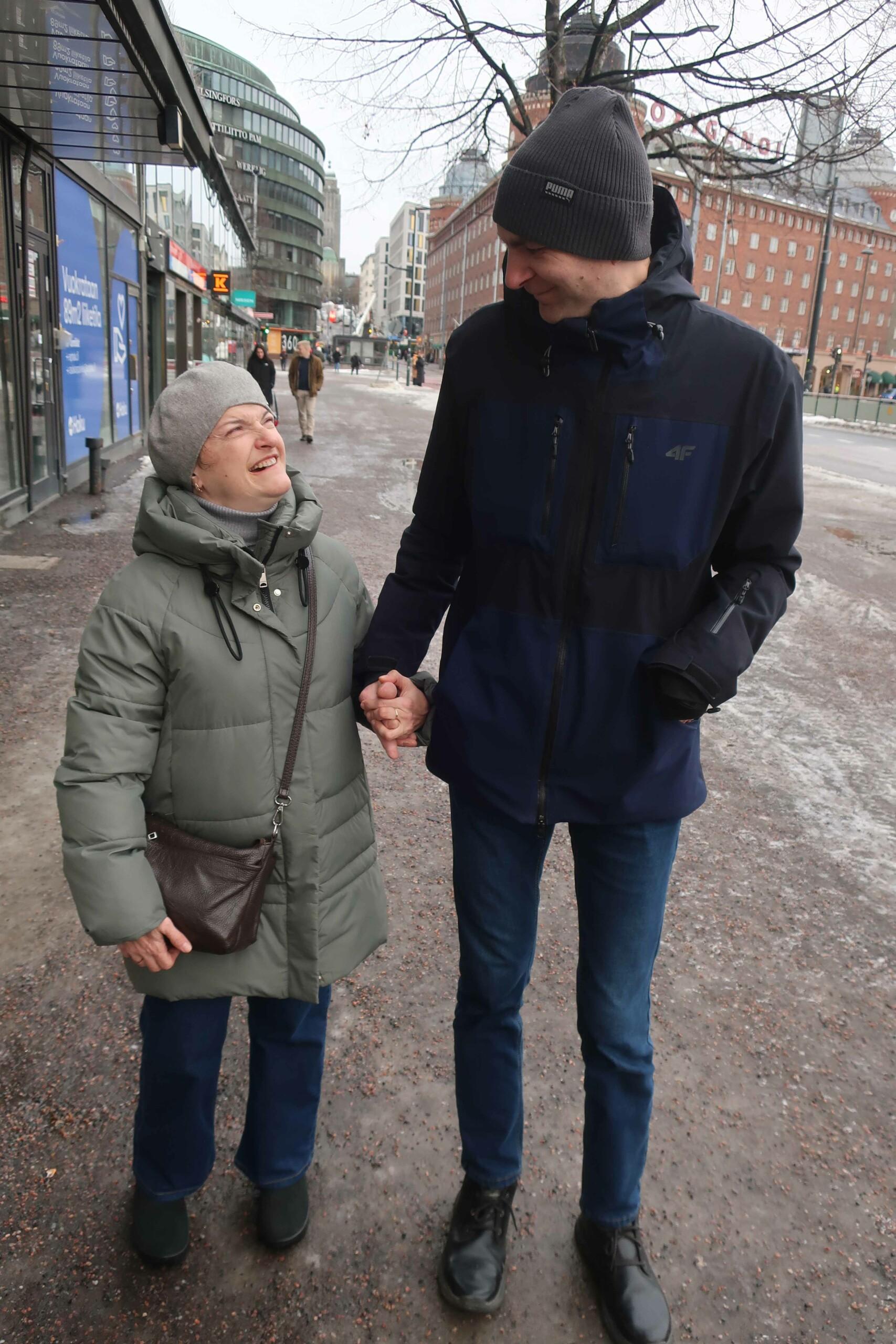 Mies ja nainen pitävät toisistaan kädestä kiinni kadulla katsoen toisiinsa.
