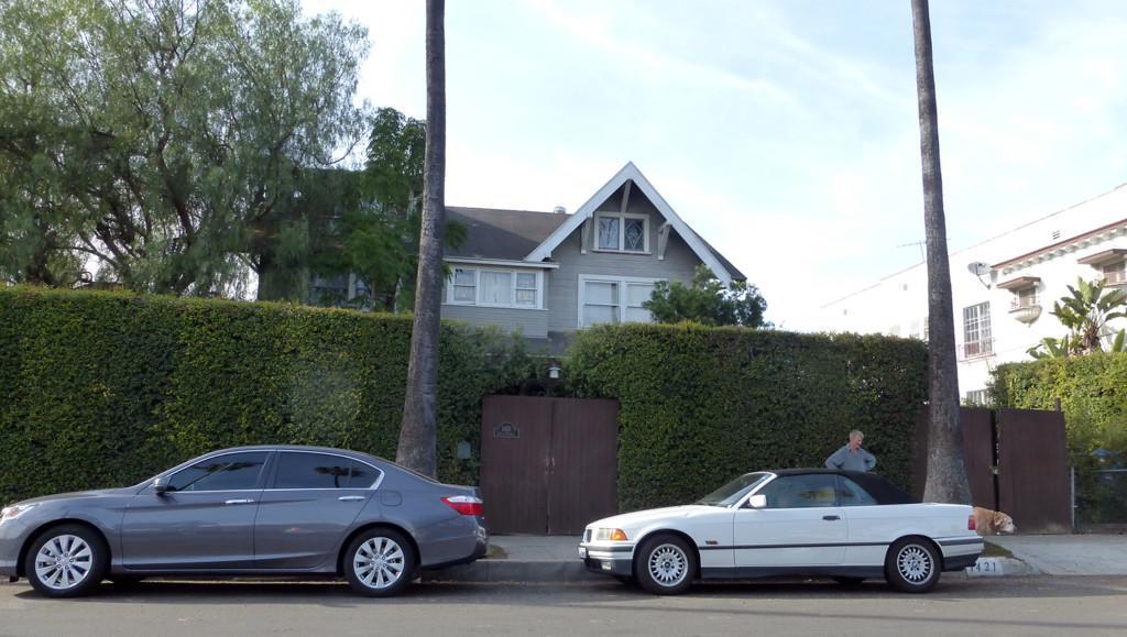 Laveta Terrace katu Los Angelesissa ja korkea pensasaita, jonka takaa pilkottaa vaaleanharmaa Tom House. Pensasaidassa on musta portti. Kadulla on Durk Dehner ja hänen vanha labradorinnoutaja koiransa. Kadulle on pysäköity kaksi autoa. 