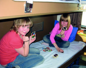 Kaksi koululaista pelaa korttia junan makuuvaunun alasängyllä leirikoulumatkalla